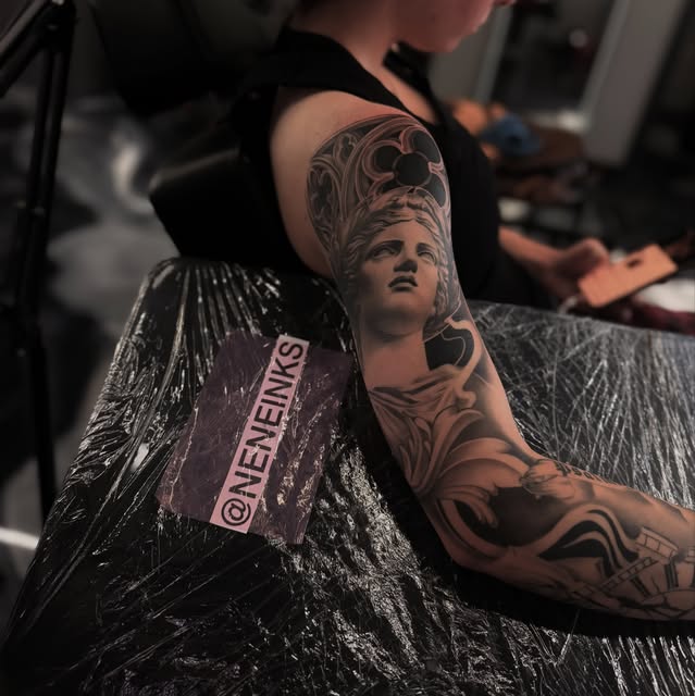 Detailed black-and-grey classical statue tattoo on an arm
